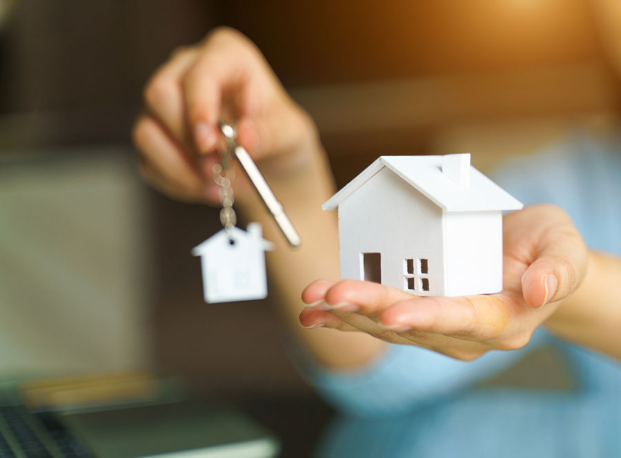 Une main tend une clé et une maison miniature