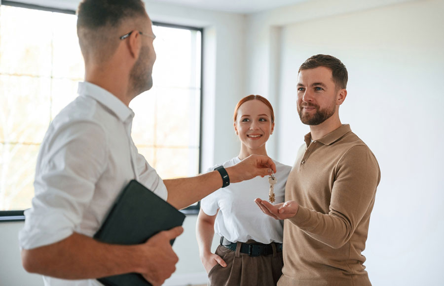 Agent immobilier avec un couple qui remet les clés d'un logement