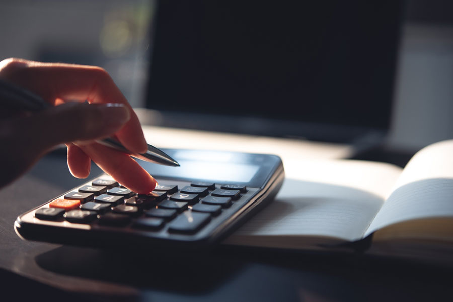 Une main avec un stylo et une calculatrice